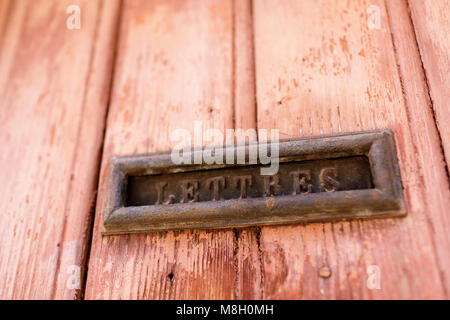 Boîte de lettres en laiton sur l'ocre rustique porte de bois dans le village de Roussillon, Provence, France Banque D'Images