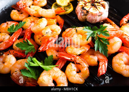 Gambas grillés sur grill poêle avec du citron et l'ail. Les crevettes grillées. Les fruits de mer. Libre. Fond sombre Banque D'Images