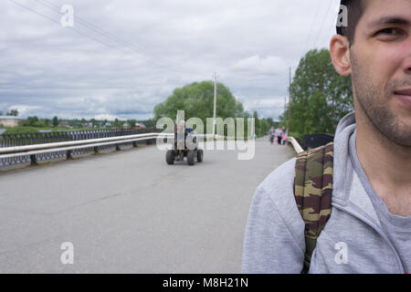 Jeune homme avec barbe hippie confiant dans les verres posant dans la rue . Cute homme portant un gilet, chemise noire et un pantalon léger. Man Banque D'Images