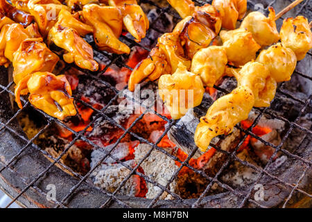 Des morceaux de poulpes, calmars, en brochettes sont frits sur un barbecue, bbq, en vente au marché de Nonthaburi Banque D'Images