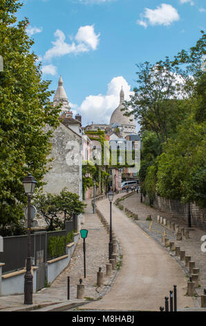 Vue de la route sinueuse s'enfuir entre les trottoirs pavés et vert des arbres sur rue avec l'architecture ancienne à Paris, France Banque D'Images