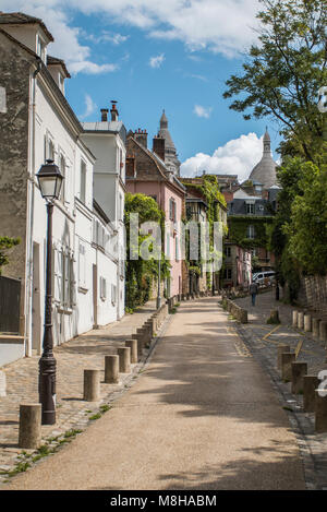 Vue de la route sinueuse s'enfuir entre les trottoirs pavés et vert des arbres sur rue avec l'architecture ancienne à Paris, France Banque D'Images