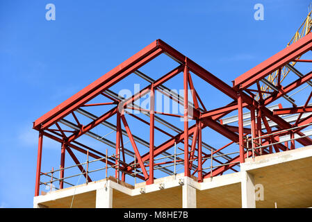 Construction de bâtiments en cours. Apprêt rouge peint en acier. Charpente rsj de solives en acier laminées. Ciel bleu Banque D'Images