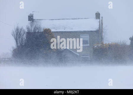 Barnard Castle, comté de Durham. Dimanche 18 mars 2018. Météo britannique. Comme la conduite d'explosions de neige passé une maison dans le comté de Durham, à seulement quelques mètres des batailles d'une femme dans la neige profonde et conditions de blizzard dans l'entreprise à la périphérie de Barnard Castle. David Forster/Alamy Live News Banque D'Images