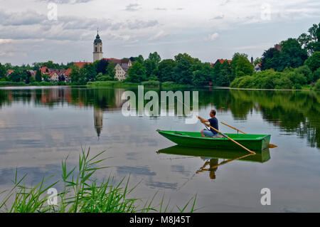 Kißlegg (Kisslegg) dans l'Allgäu: Pêcheur dans un petit bateau sur le 'Zeller See', ville avec steeple en arrière-plan, Bade-Wurtemberg, Allemagne Banque D'Images