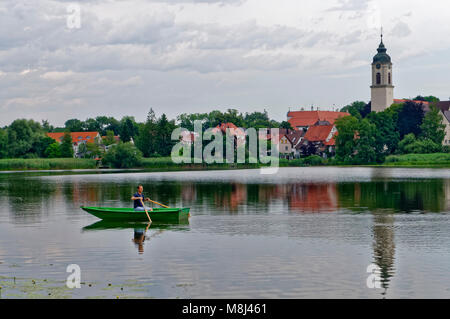 Kißlegg (Kisslegg) dans l'Allgäu: Pêcheur dans un petit bateau sur le 'Zeller See', ville avec steeple en arrière-plan, Bade-Wurtemberg, Allemagne Banque D'Images