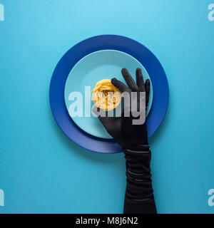 Concept créatif photo d'ustensiles de cuisine avec plaque peinte à la main, avec de la nourriture sur elle sur fond bleu. Banque D'Images