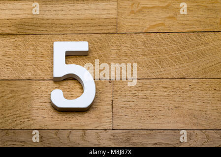 Numéro cinq sur le parquet en bois en arrière-plan. Banque D'Images