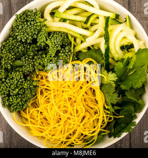 Végétarien ou Végétalien sain Bol Bouddha nouilles aux courgettes et brocoli coriandre sur un dessus de table de cuisine en bois foncé Banque D'Images