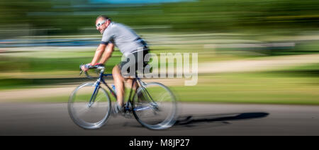 Le port de lunettes cycliste blanc courses autour de Richmond Park dans le flou Banque D'Images