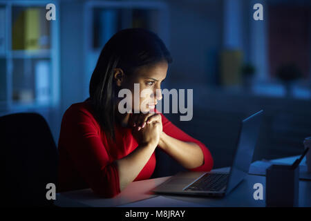 Employé de bureau de fin de nuit des heures supplémentaires. White collar worker working on computer dans la nuit dans le bureau sombre. Banque D'Images