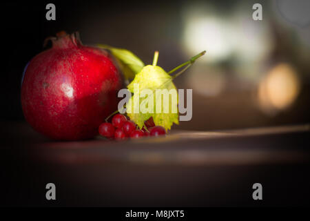 Avec pomegranade Naturemort, fruits rouges et des feuilles jaunes Banque D'Images