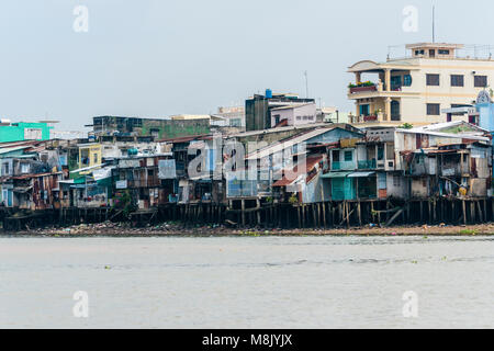 Les maisons sur pilotis de fortune faits de tôle ondulée, feuilles de bois et autres matériaux de construction sur les rives de la rivière Meekong, Vietnam Banque D'Images