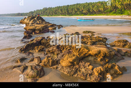 Chera rock en plein milieu de la plage de sable fin bordée de palmiers et de bateau en bois donnant sur la mer d'Oman au coucher du soleil près de Thottada village, New Delhi, Inde. Banque D'Images