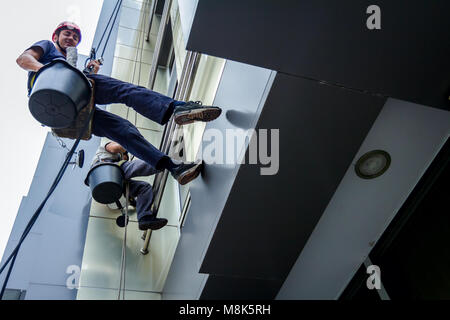 Les deux alpinistes sont lavage, nettoyage façade d'un immeuble de bureaux modernes. Ciel nuageux en arrière-plan. Banque D'Images