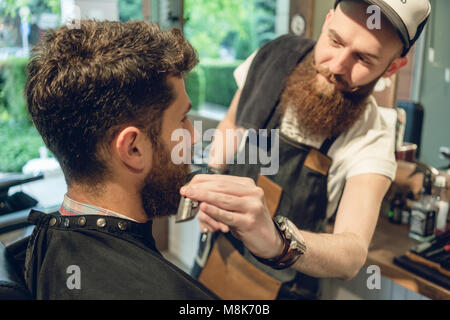 Beau jeune homme assis sur le fauteuil d'un coiffeur Banque D'Images