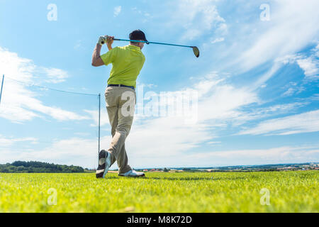 L'homme dans la position de finition d'un swing de conduite tout en jouant au golf Banque D'Images