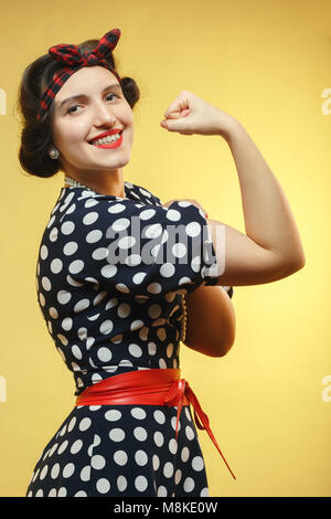 Strong Woman show ses biceps sur fond jaune looking at camera Banque D'Images