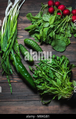 Arrière-plan de printemps avec des légumes juteux comme les oignons verts, la roquette, les concombres et les radis. Concept d'aliments sains. La nourriture végétalienne. Banque D'Images