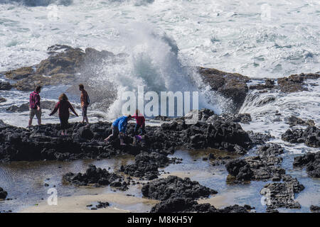 Courageux touristes le fracas des vagues d'explorer Thor va bien à Cape Perpetua Scenic Area, New York Banque D'Images