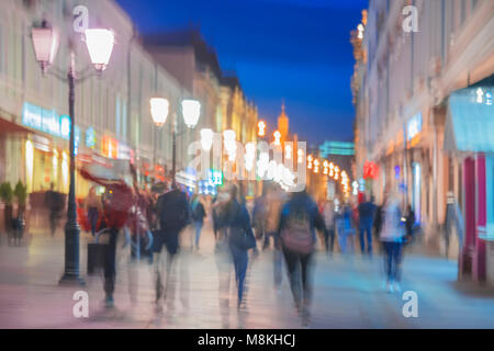 Image abstraite de silhouettes méconnaissables de personnes marcher dans la ville street dans la soirée, shopping, vie nocturne. Contexte moderne urbaine. Effet de mouvement floue Banque D'Images