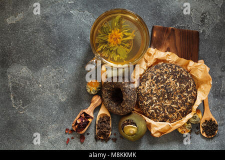 Différentes sortes de thé ; Asian enfoncé le thé pu-erh, shu Pu'er dans la mandarine, fleurs de thé dans la région de ball sur fond d'ardoise sombre vue de dessus Banque D'Images