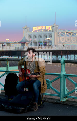 Un musicien ambulant divertit les passants par des chants et de la guitare sur la promenade près de la célèbre jetée de Brighton, l'une des destinations touristiques les plus populaires. Banque D'Images