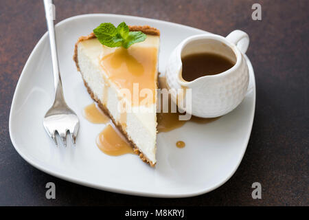 Gâteau au fromage avec coulis de caramel sur plaque blanche, vue rapprochée, selective focus. Tranche de gâteau au fromage, gâteau au caramel Banque D'Images