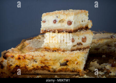 Libre de deux morceaux de gâteau au fromage fait à la main avec des raisins se tient sur son ensemble pie servi sur tablette en bois contre l'arrière-plan gris Banque D'Images