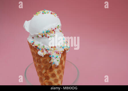 Cornet de crème glacée avec boule de glace à la vanille et confettis en verre isolé sur fond rose. vue d'en haut. Parti, dessert, été, concept. Banque D'Images