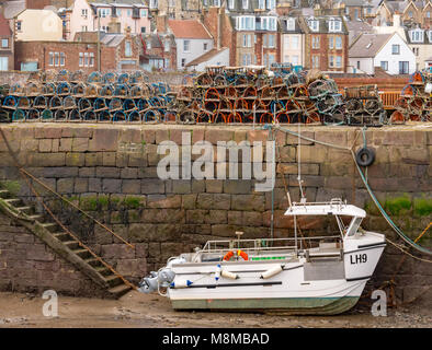 North Berwick, East Lothian, Ecosse, Royaume-Uni, 19 mars 2018. Bateau de pêche échoués dans le port à marée basse avec homard à la nasse ou des pots sur le quai du port Banque D'Images