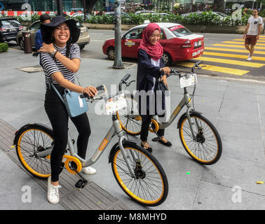 Deux filles de Malaisie sur oBikes bicyclettes, Avenue K, Jalan Ampang, KLCC, Kuala Lumpur, Malaisie Banque D'Images