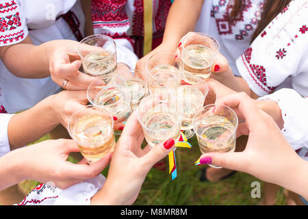 Les filles habillés en costumes nationaux traditionnels ukrainiens clinking glasses at hen party outdoors Banque D'Images