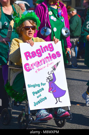 Une femme plus âgée dans un fauteuil roulant avec un panneau qui dit Raging Grannies de Whatcom Comté. Elle porte un chapeau vert et s'habiller et se trouve dans le Bel Banque D'Images