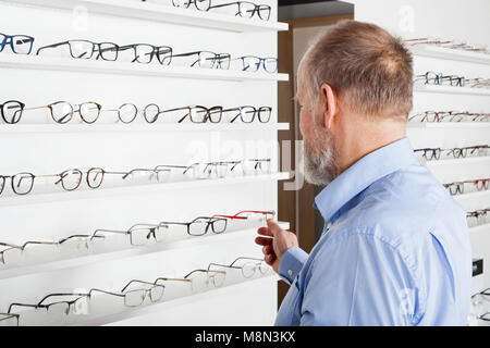 Le choix d'un homme âgé en optique lunetterie store Banque D'Images