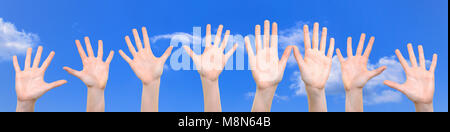 Groupe d'enfants blancs caucasiens est montrant les mains avec les paumes ouvertes sur un fond de ciel bleu en close-up ( haute résolution). Banque D'Images