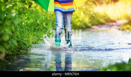 La marche de l'enfant dans la flaque en wellies sur temps de pluie Banque D'Images