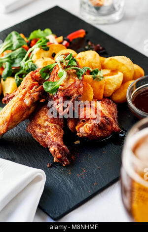 Ailes de poulet rôti avec des pommes de terre frites Banque D'Images