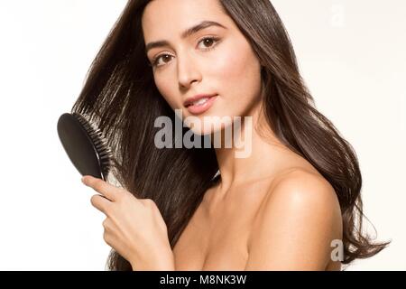 Parution du modèle. Jeune femme se brosser les cheveux bruns longs, portrait. Banque D'Images
