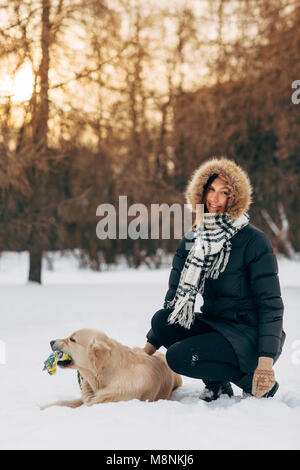 Photo de jeune fille souriante avec le labrador sur fond d'arbres dans winter park