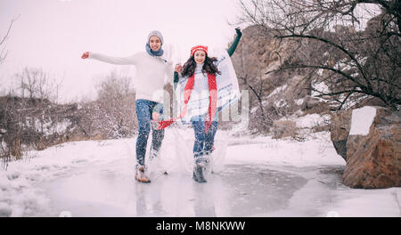 Jeune couple in a park et balades sur les couverts avec de l'eau fondue flaque. Les projections d'eau voler en dehors et les jeunes rit gaiement. Banque D'Images