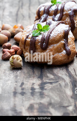 Petits pains au chocolat belge choux farci de crème aux noisettes sur table en bois Banque D'Images