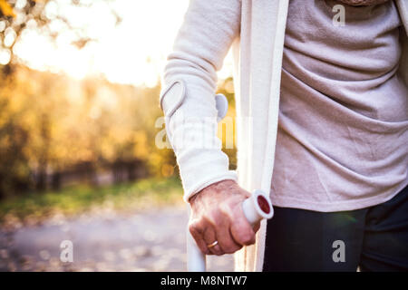 Une femme âgée avec une béquille sur une promenade en automne la nature. Banque D'Images