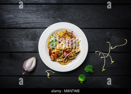 Udon nouilles sautés avec de la viande ou du poulet et légumes dans une assiette blanche. Banque D'Images