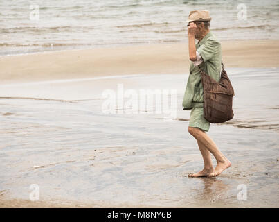 Homme âgé marche pieds nus sur la plage Banque D'Images