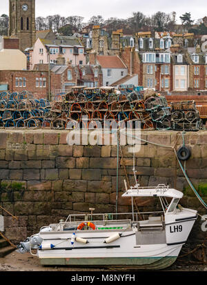 North Berwick, East Lothian, Ecosse, Royaume-Uni, de bateaux échoués dans le port à marée basse avec homard à la nasse sur la jetée. Maisons en bord de mer en arrière-plan Banque D'Images