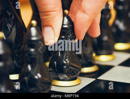 Personne doigts avec pion noir fait de déplacer d'abord sur l'échiquier. Close-up. Banque D'Images