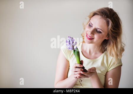 Jeune femme tenant une fleur à la maison des semis. Banque D'Images