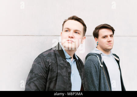 Deux amis adolescents de sexe masculin ou brothers leaning against wall Banque D'Images