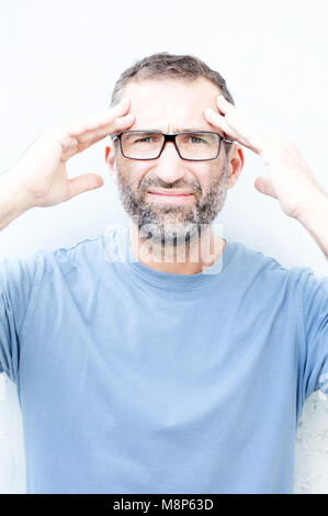 Beau portrait d'homme barbu avec des lunettes ayant un mal de tête Banque D'Images
